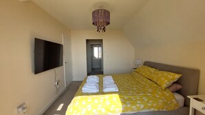A bedroom with a bed, a TV, and a chandelier.