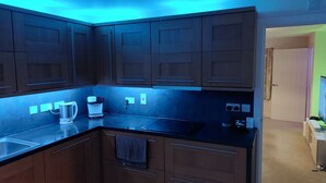 A modern kitchen with dark wooden cabinets, a black countertop, and a coffee maker.