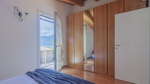 A bedroom with a bed, a wardrobe, and a sliding door leading to a balcony. - Magic Lake View in Lierna (Lierna)