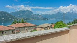 A coastal town with buildings overlooking a lake, mountains in the background, and a power line tower. - Magic Lake View in Lierna (Lierna)