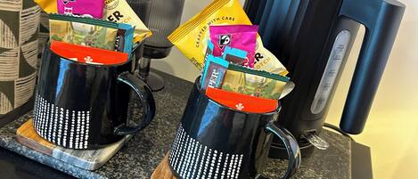 Dos cafeteras sobre una encimera de granito, con una cafetera y un hervidor.