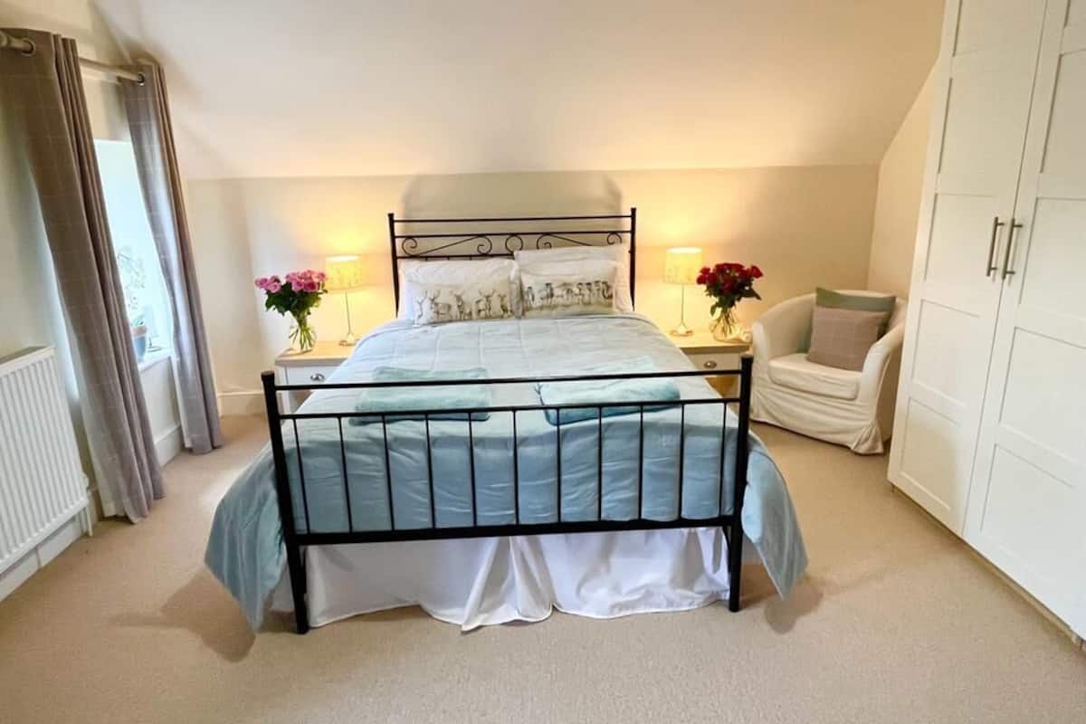 A bedroom with a bed, bedside tables, a chair, and a wardrobe.