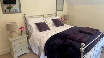 A neatly made bed with a metal frame, two bedside tables with lamps, and a mirror on the wall.