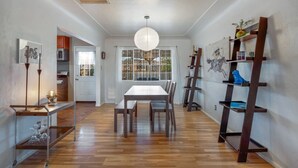 Un coin repas avec une table en bois, des chaises, une suspension et une fenêtre donnant sur un beau paysage.