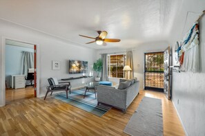A modern living room with a grey sofa, a dining table, and a ceiling fan.