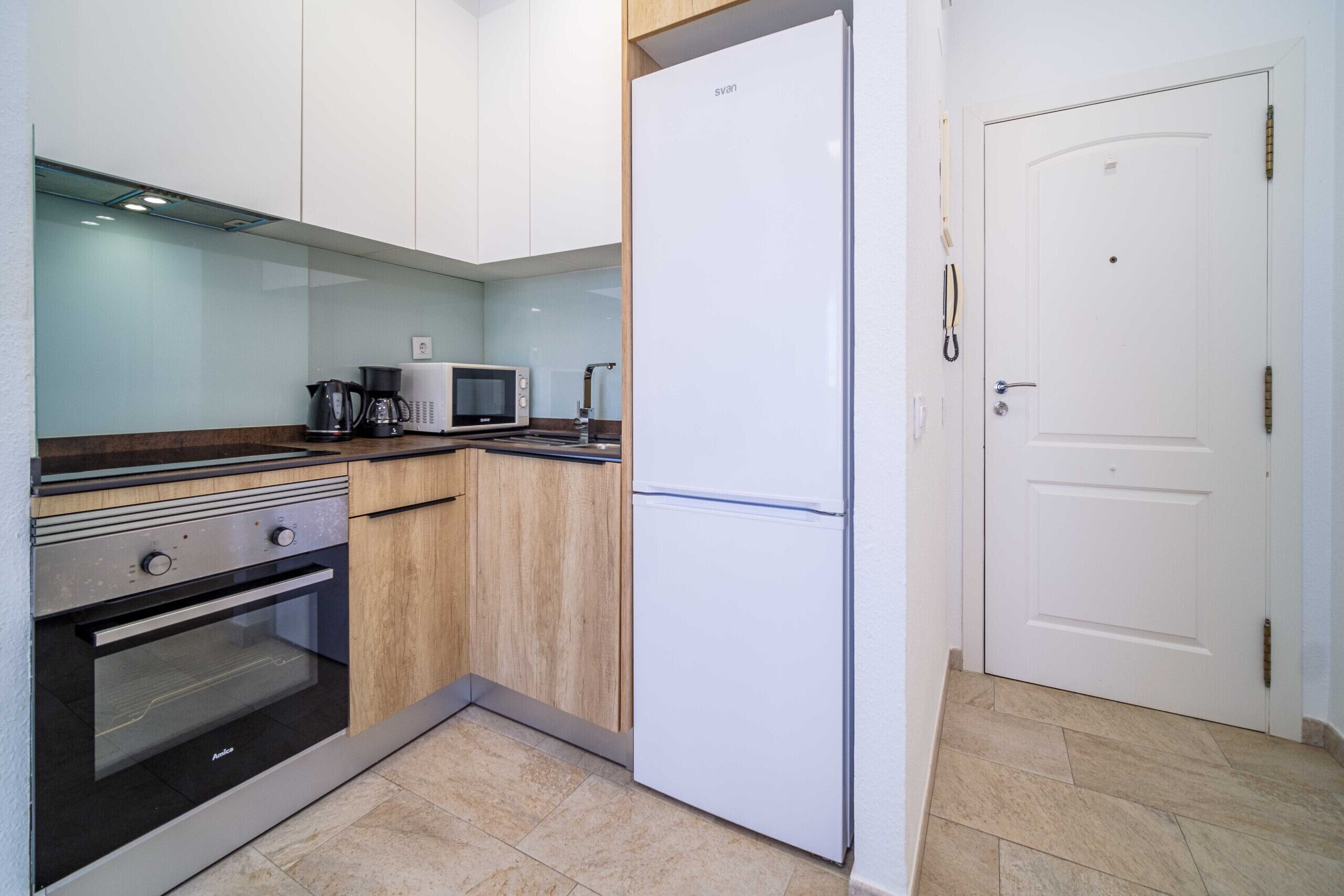 A kitchen with white cabinets, a stainless steel oven, a microwave, and a white refrigerator.