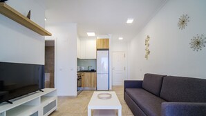 Un salon moderne avec un téléviseur à écran plat, un canapé gris et une table basse blanche.
