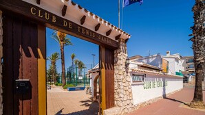 L’entrée du Club de Tennis de Jávea se distingue par un mur en pierre et des portes en bois.