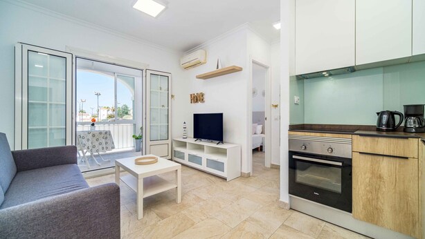 Un appartement moderne comprenant un espace de vie, une kitchenette et un balcon avec une table et des chaises.