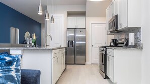 Una cocina moderna con armarios blancos, electrodomésticos de acero inoxidable y una pared de acento azul.