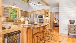 Una cocina moderna con armarios de madera, electrodomésticos de acero inoxidable y una isla grande con taburetes de bar.
