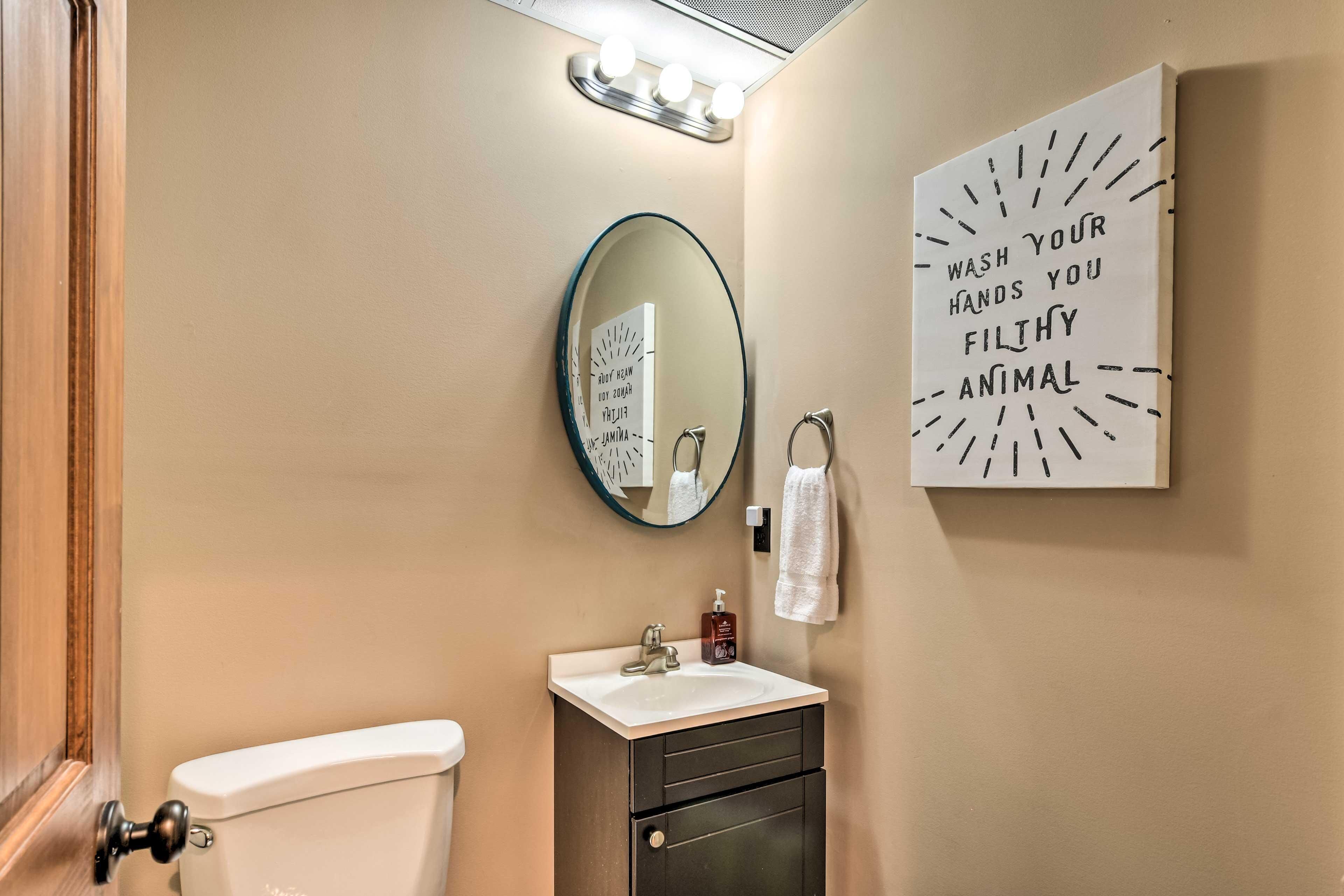 A bathroom with a toilet, sink, and mirror. There is a sign on the wall that says "WASH YOUR HANDS YOU FILTHY ANIMAL".