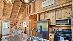 Ein Holzblockhaus-Interieur mit einer Küche, die einen Edelstahl-Kühlschrank, einen Backofen und eine Mikrowelle beinhaltet.