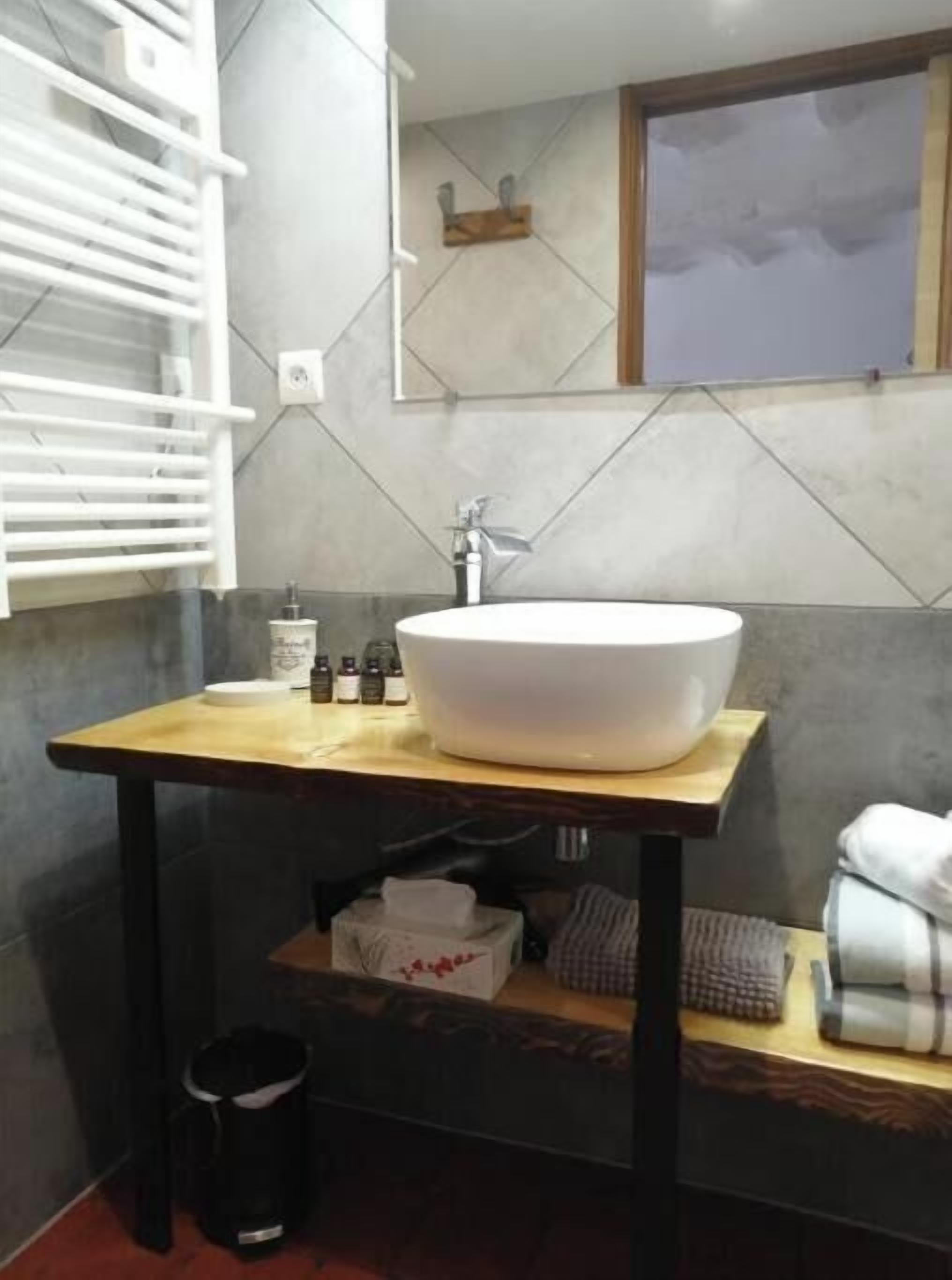 Une salle de bain avec un grand lavabo blanc, un porte-serviettes et une petite étagère contenant des articles de toilette.