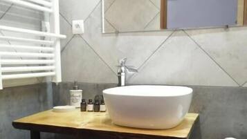 Une salle de bain avec un grand lavabo blanc, un porte-serviettes et une petite étagère contenant des articles de toilette.