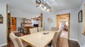 Un espace repas comprenant une grande table, des chaises et un lustre de style rustique.