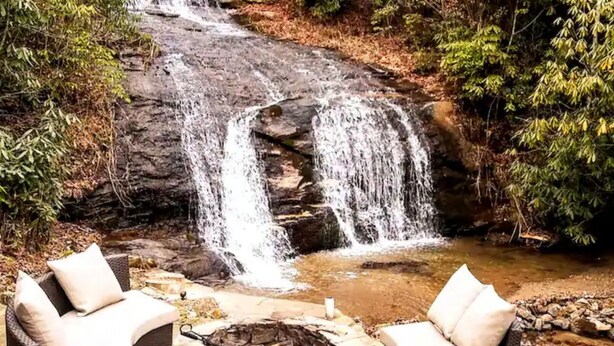 Une cascade située dans un cadre naturel, avec un espace extérieur aménagé pour s’asseoir et un foyer.