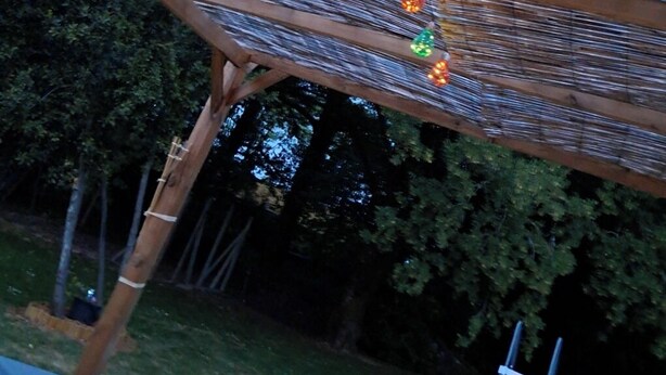 A wooden structure with horizontal slats and colorful string lights. - Au Doux Rêves (Corgnac-sur-l'Isle)