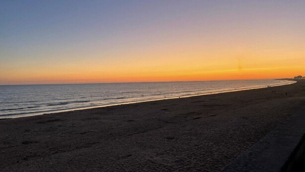 Een strand bij zonsondergang, met een heldere lucht.