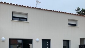Een modern gebouw met een plat dak, twee ramen, een deur en een schotelantenne.