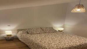 Een slaapkamer met een bed met een patroon, twee bedlampen en een hanglamp.