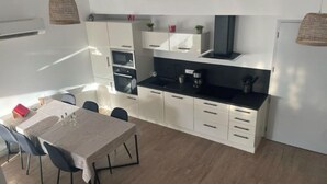 Een moderne keuken met witte kasten, een zwart aanrecht en een dakraam boven de eethoek.