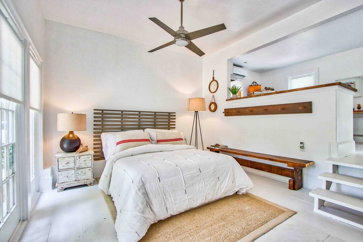 A bedroom with a bed, bedside table, lamp, and a ceiling fan.