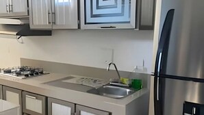 A modern kitchen with stainless steel appliances, a built-in oven, and a central island with a sink.