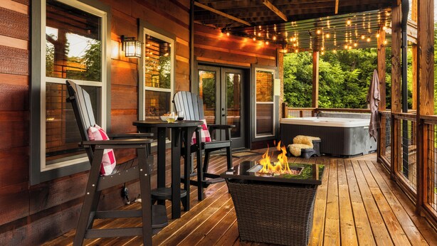 Une terrasse en bois avec des sièges d’extérieur, un jacuzzi et des guirlandes lumineuses.
