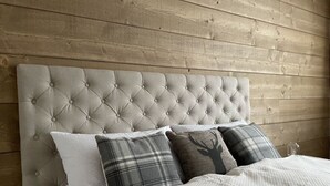 Una cama con cabecera capitonada, ropa de cama blanca y tres almohadas en estampados y colores lisos.