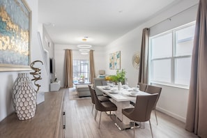 A modern dining area with a long table, chairs, and a vase on the sideboard. - Magic Manor by Avantstay Pool 30min to Disney (Davenport)