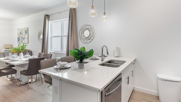 Una cocina moderna con una isla central, electrodomésticos de acero inoxidable e iluminación colgante.