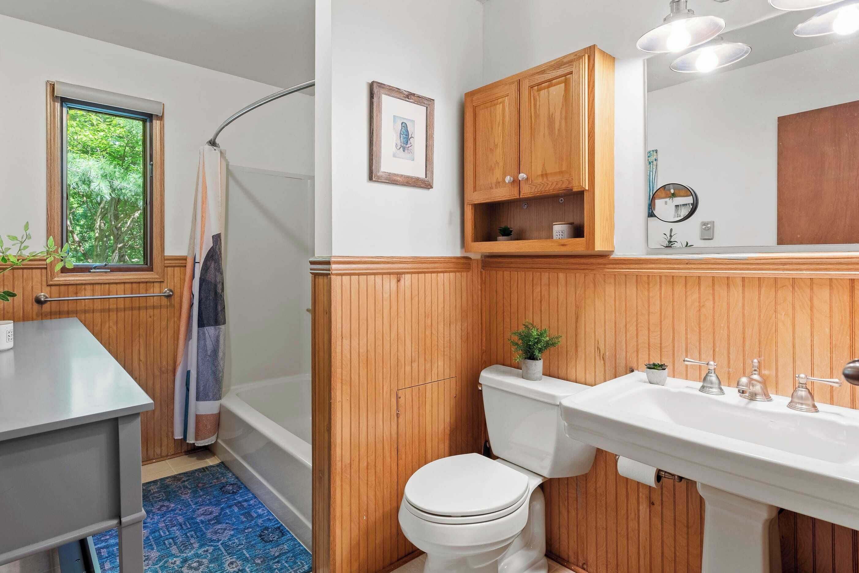 Un baño con tocador de madera, lavamanos, inodoro e hidromasaje.
