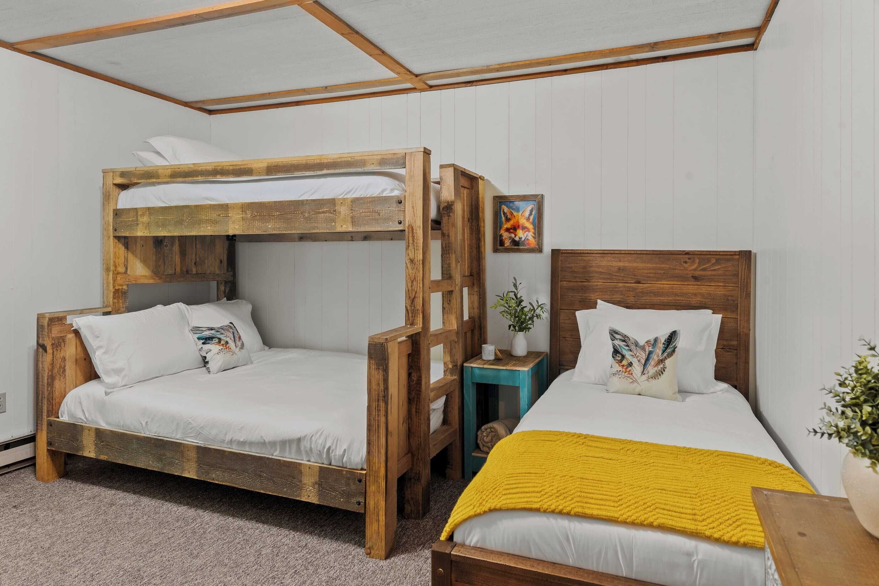 A room with two bunk beds, a small table with a plant, and a painting on the wall.