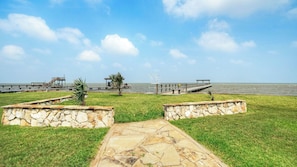 Un sentiero in pietra conduce a una zona sul lungomare, con un molo e un gazebo.