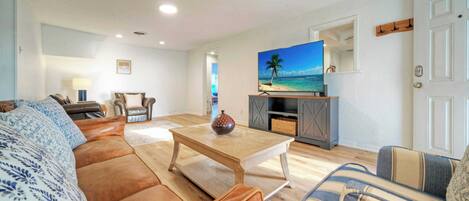 Una sala de estar con un sofá, una mesa de centro y un televisor sobre un mueble.