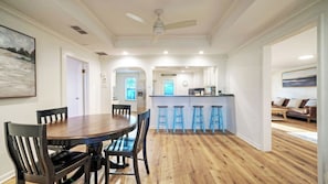 Una sala da pranzo con tavolo e sedie in legno, una cucina con angolo bar e un soggiorno con divano.