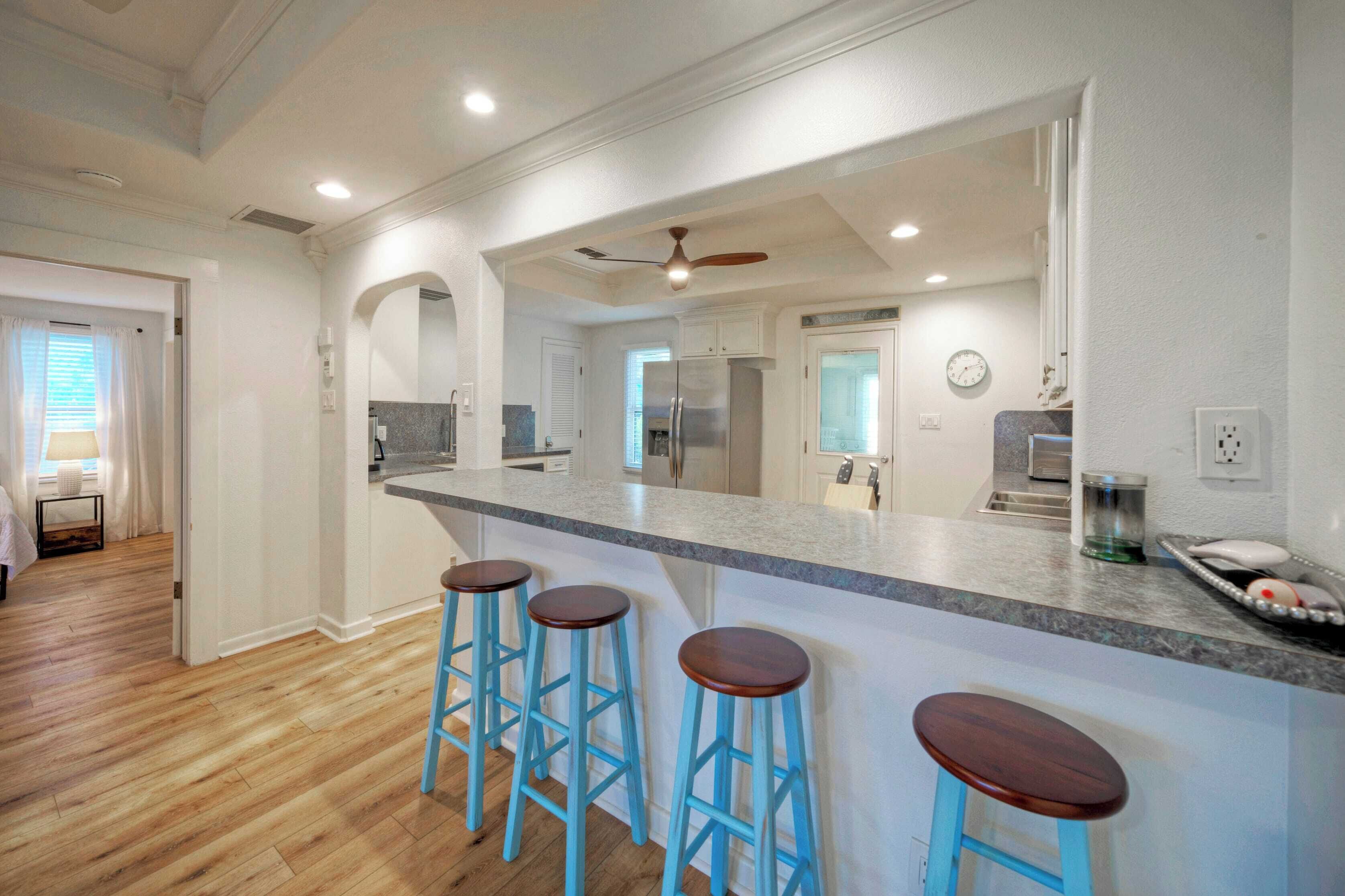 A modern kitchen with a central island, bar stools, and a refrigerator.