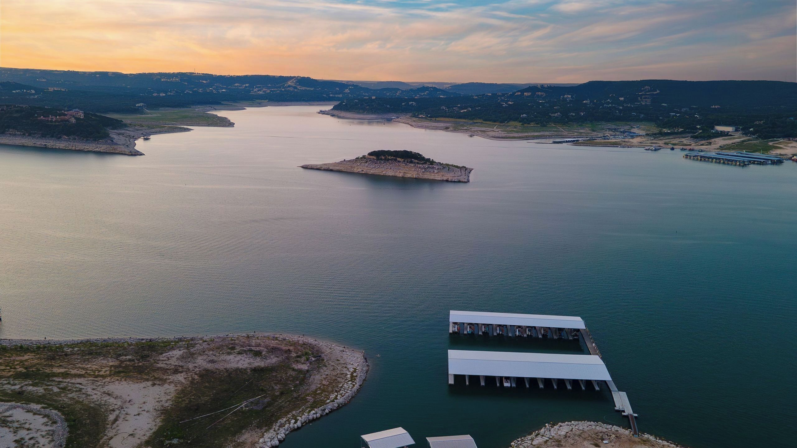 An aerial view of a lake with a small island and a dock extending into the water.