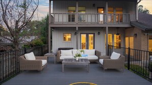 A two-story house with a balcony, outdoor furniture, and a small table. - Travis by Avantstay Waterfront Lake Retreat (Austin)