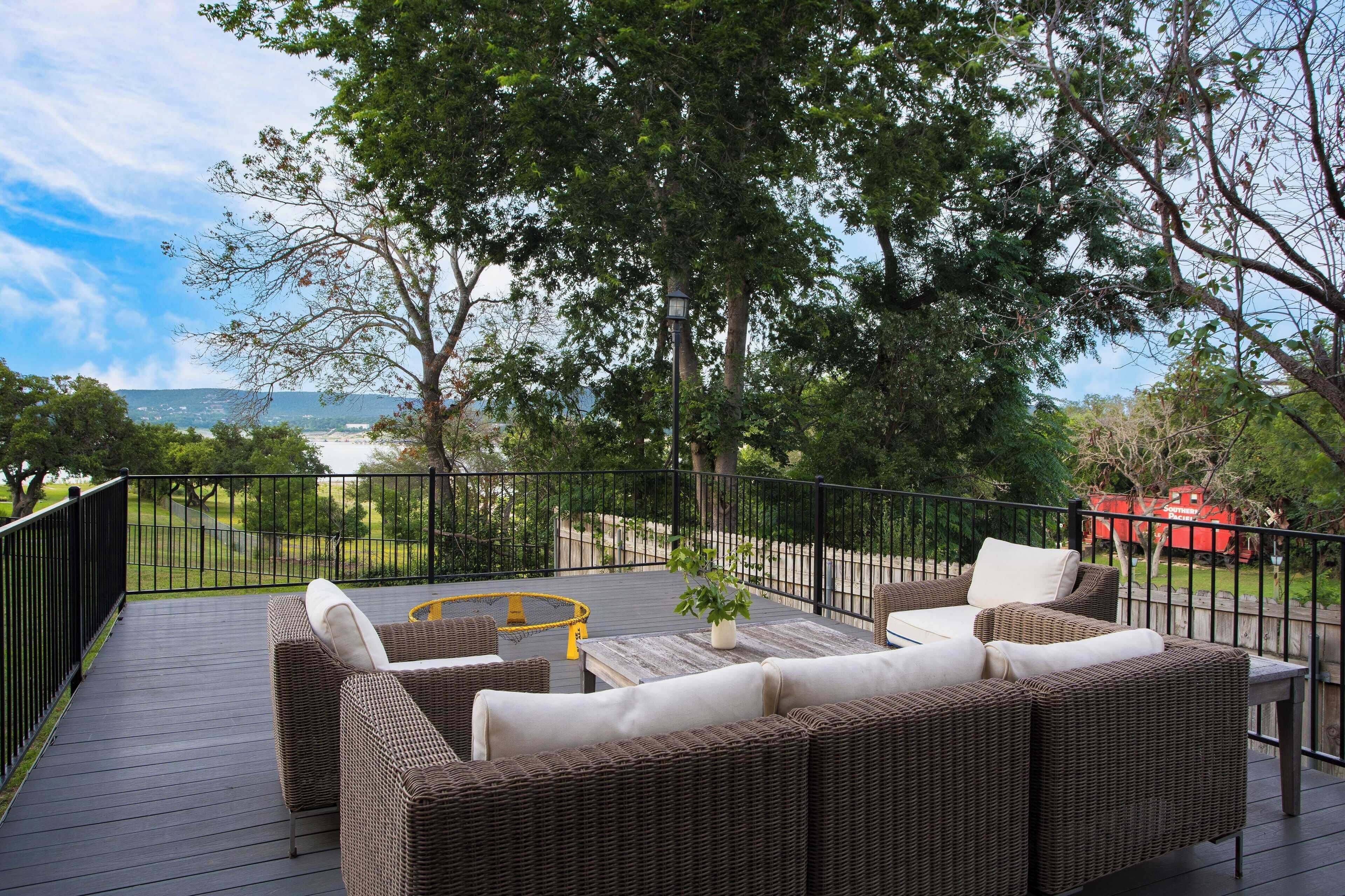 Um terraço com móveis de vime, uma pequena mesa e vista para a paisagem.