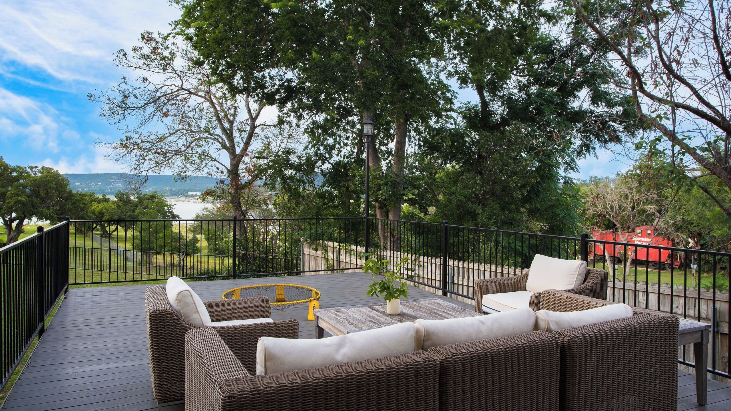 Eine Terrasse mit Korbmöbeln, einem kleinen Tisch und einem Blumentopf.