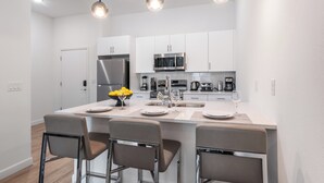 A modern kitchen with white cabinets, stainless steel appliances, and a central island with bar stools.