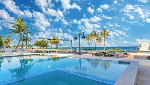 A swimming pool with lounge chairs, palm trees, and a view of the ocean. - Rate Discounts! Beachside Home, Pool + Ocean Views Beach Haven by Avantstay (Fort Lauderdale)