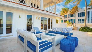 A modern outdoor seating area with blue and white furniture, large windows, and palm trees.