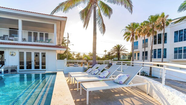 A pool area with lounge chairs and a building with balconies. - Rate Discounts! Beachside Home, Pool + Ocean Views Beach Haven by Avantstay (Fort Lauderdale)