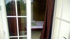 A room with a bed, a wardrobe, and a sliding glass door leading to another room. - Espaciosa y Comoda Casa en Frente de la Plazajazz (Santa Cruz de Mompox)