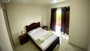 A bedroom with a bed, bedside tables, a window with curtains, and a ceiling light. - Espaciosa y Comoda Casa en Frente de la Plazajazz (Santa Cruz de Mompox)