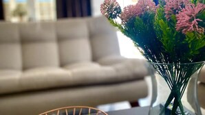 A modern living room with a white sofa, a glass vase with pink flowers, and a geometric wire basket on a dark table. - Espaciosa y Comoda Casa en Frente de la Plazajazz (Santa Cruz de Mompox)
