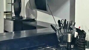 A kitchen with a gas stove, a range hood, and a knife block on the counter.